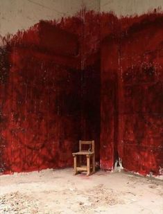 a wooden chair sitting in front of a red wall