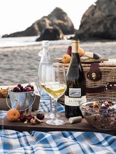 a picnic with wine, fruit and bread on the beach