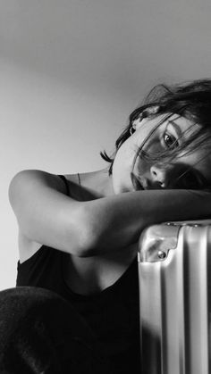 black and white photograph of a woman leaning on an old metal radiator with her arms crossed