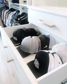 several hats are sitting in a drawer on top of a white table and some drawers