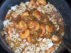 shrimp and rice in a sauce being stirred with a spoon