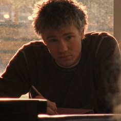 a young man sitting at a table with a pen in his hand