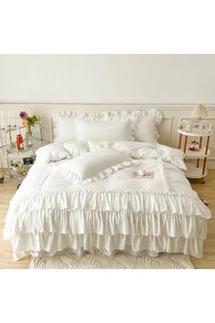 a white bed with ruffled sheets and pillows