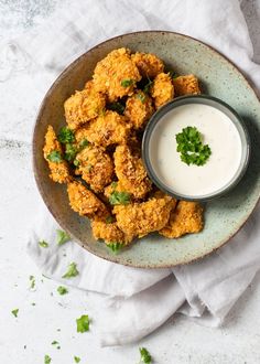 a bowl filled with fried food next to a cup of ranch dressing