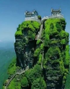 an aerial view of a mountain with a castle on it's cliff face, surrounded by greenery