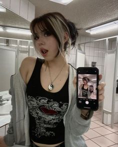 a woman holding up a cell phone in a bathroom