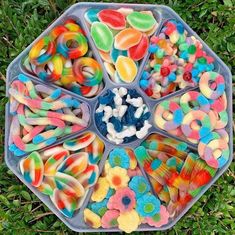 a tray filled with lots of different types of candies on top of green grass