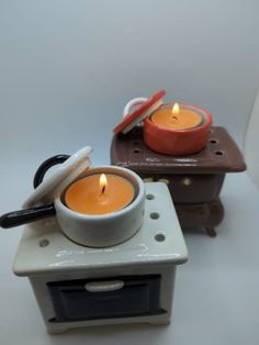 two small candles sitting on top of a white table next to a brown and red box