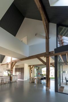 a large open living room and kitchen area with wood beams on the ceiling, white walls and flooring