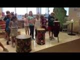 a group of young people standing around each other in a room with drums on the floor