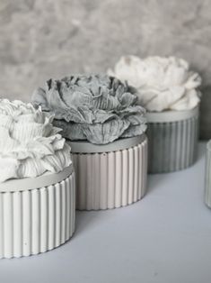 three white and gray vases with flowers in them