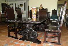 a dining room table with chairs and a vase on it's end, in front of a tiled floor