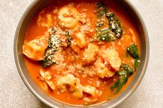 a bowl filled with pasta and spinach on top of a table