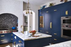 a kitchen with blue cabinets, marble counter tops and stainless steel ovens in it