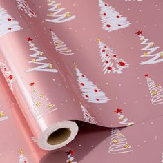 a pink christmas wrapping paper with white trees on it and gold stars in the background