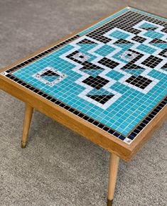 a coffee table with blue and black tiles on it's top, sitting on the floor