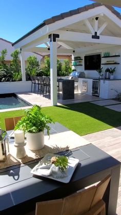 an outdoor kitchen and dining area with pool in the background