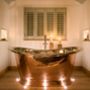 a bath tub sitting in the middle of a bathroom next to a window with candles on it