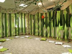 the room is decorated with green and white striped walls, paper streamers, and pillows on the floor