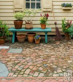 several potted plants are sitting on a blue bench in front of a yellow house