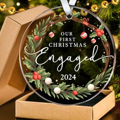 personalized christmas ornament with holly wreath and baubles on it in front of a christmas tree