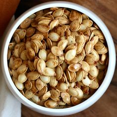 a white bowl filled with nuts on top of a wooden table