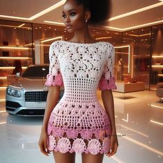 a crocheted dress is displayed in front of a white car with pink flowers