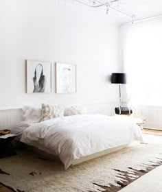 a white bedroom with two pictures on the wall