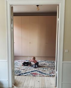 a toddler playing with a toy car in the middle of an empty living room