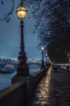 a lamp post on the side of a river at night