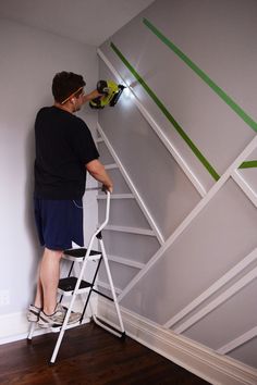 a man on a ladder painting the wall