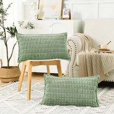 two green pillows sitting on top of a white rug next to a chair and potted plant