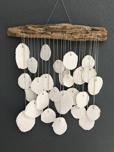 a group of white ornaments hanging from a wooden stick on a wall next to a gray wall