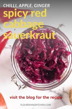 red cabbage sauerkraut in a glass jar on a marble counter top with the title, spicyred cabbage sauerkraut visit the blog for the recipe