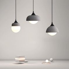 three lights are hanging from the ceiling in an empty room with white and gray walls