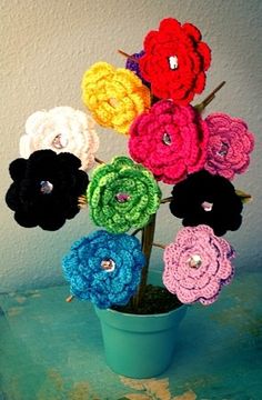 crocheted flowers are arranged in a pot on top of a blue countertop