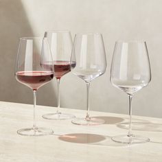 three wine glasses sitting on top of a table next to each other with different colored wines in them