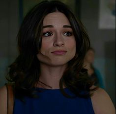 a close up of a person wearing a blue dress and looking at the camera with a serious look on her face