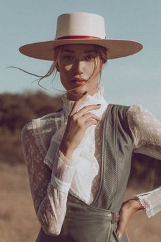 a woman wearing a white hat and dress shirt is posing for the camera with her hands on her hips