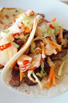 three tacos with meat and vegetables on a plate