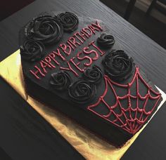 a black and red birthday cake with spider web on the top is sitting on a table