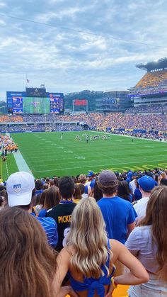 a group of people watching a football game on a cloudy day at an outdoor stadium