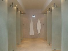 an empty bathroom with two white robes hanging on the wall