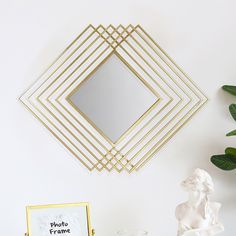 a white table topped with a vase filled with flowers next to a gold framed mirror