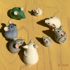 small ceramic mouses are arranged in a circle on a wooden surface, including one with an animal's head