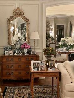 a living room filled with lots of furniture and flowers on top of a wooden table