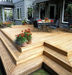 a wooden deck with chairs and flowers on it