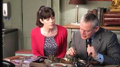 a man and woman sitting at a table with many items in front of them on it