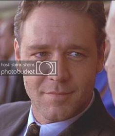 a close up of a person wearing a suit and tie with other people in the background