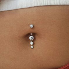 a woman's belly with three diamond studs attached to the back of her stomach